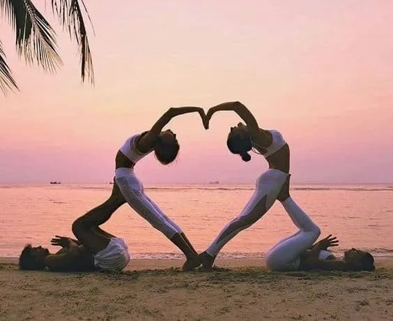 Nhóm 4 người thực hiện tư thế yoga nhóm với gập người và vươn tay