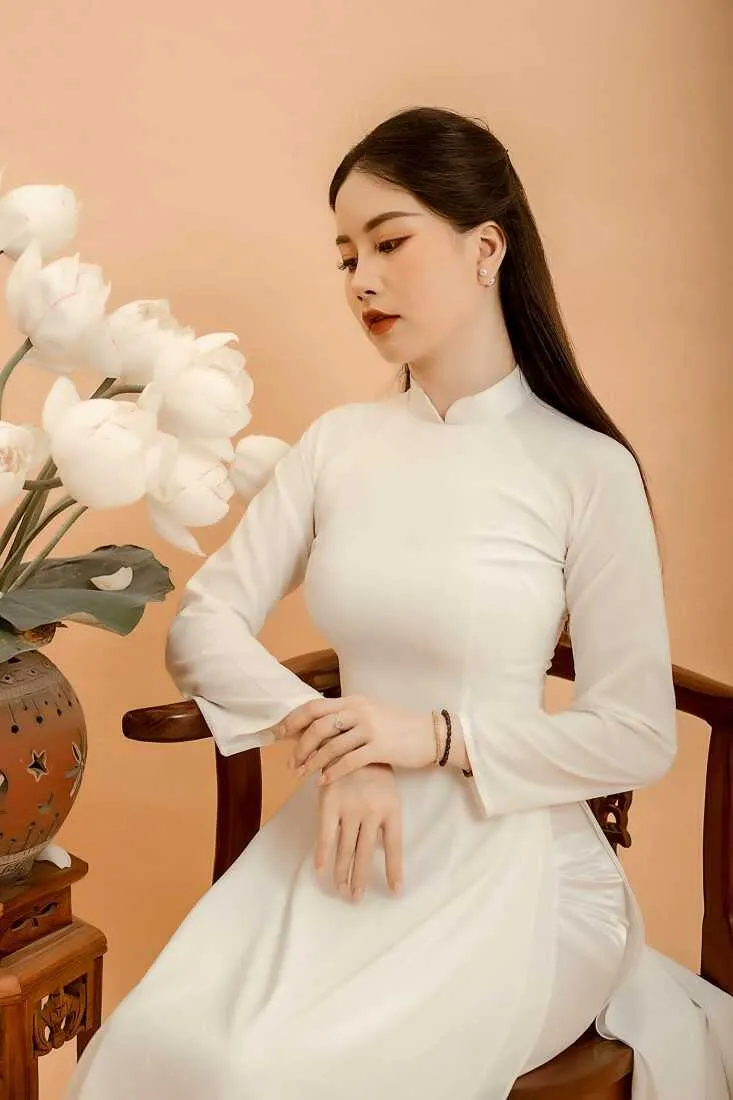 Cô gái ngồi cạnh bình sen trong nhà