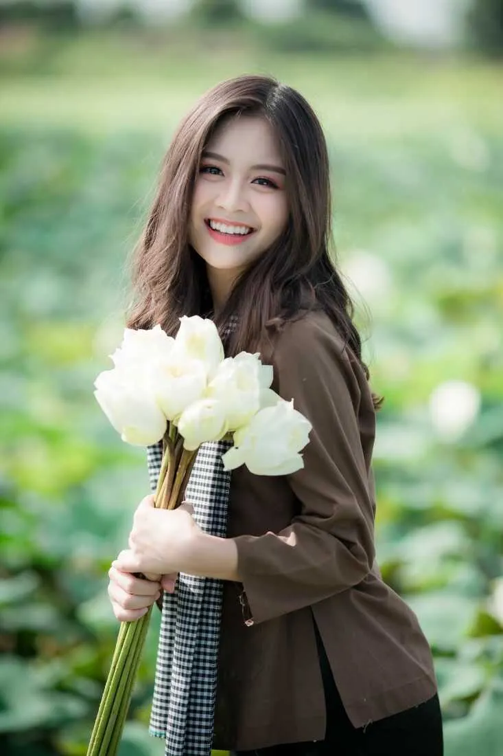 Cô gái mặc áo bà ba ngồi trên thuyền giữa đầm sen