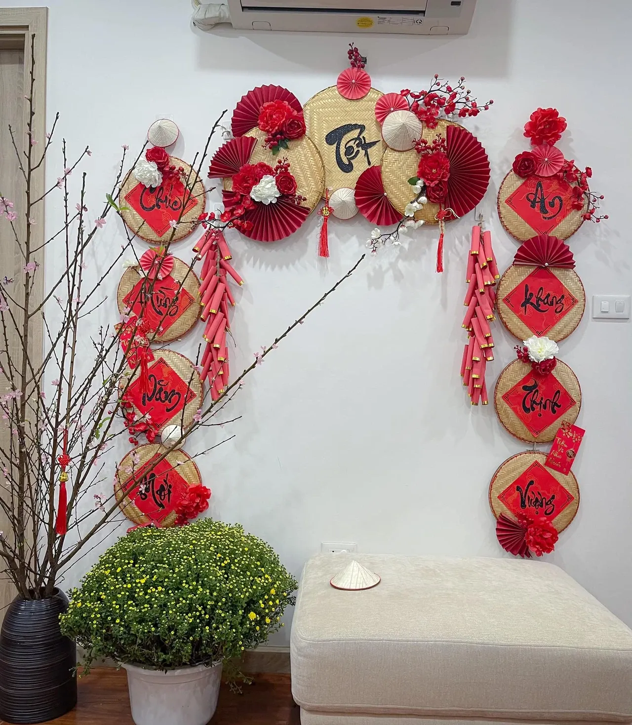 Dây pháo giấy đỏ và quạt giấy trang trí trên tường, kết hợp chậu cây cảnh tạo không khí Tết