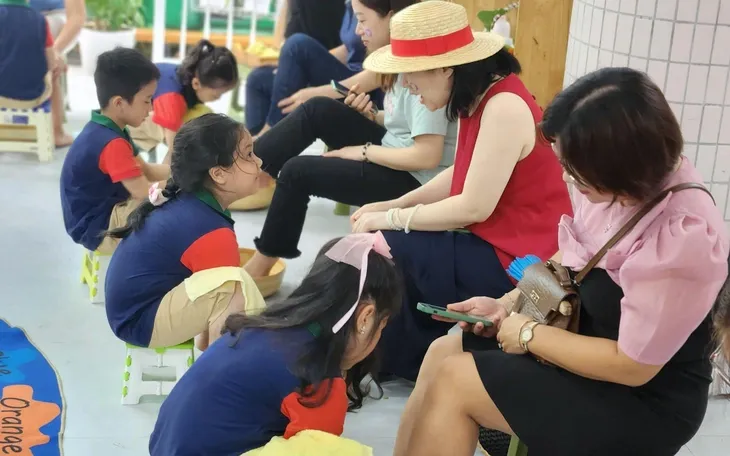 Phụ huynh chụp ảnh cùng con trong trang phục cử nhân mầm non, lưu giữ hình tốt nghiệp mầm non