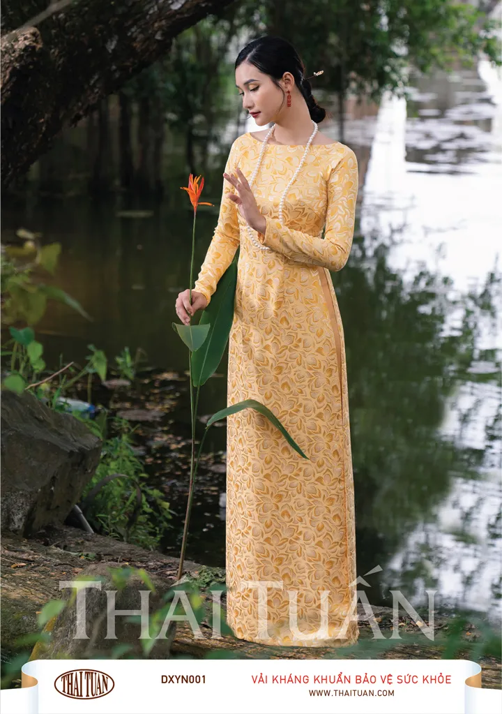 Áo dài gấm vàng rực rỡ với họa tiết hoa văn đối xứng.