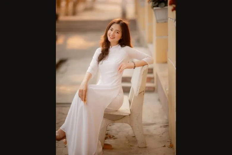 Nữ sinh áo dài trắng ngồi ghế đá sân trường, nhìn xa xăm