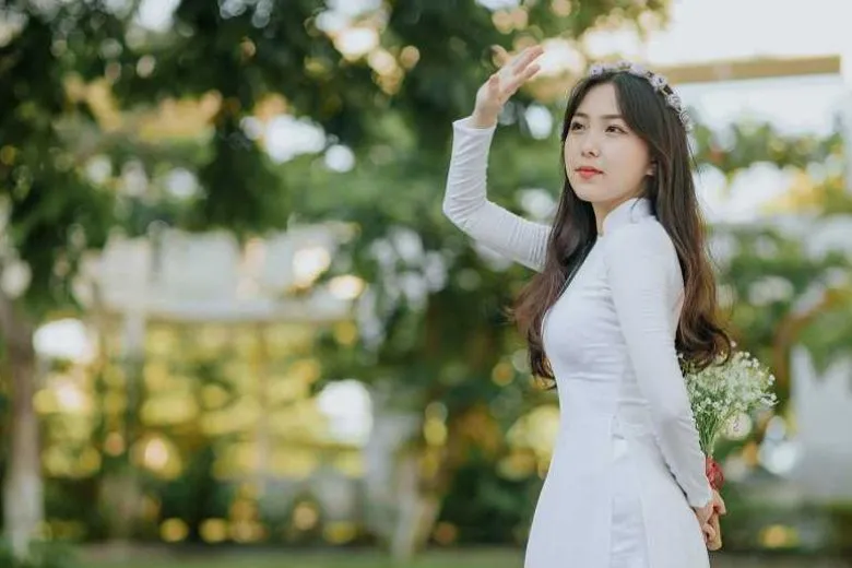 Nữ sinh áo dài trắng tạo dáng góc nghiêng, tay nhẹ nhàng chạm vào tóc