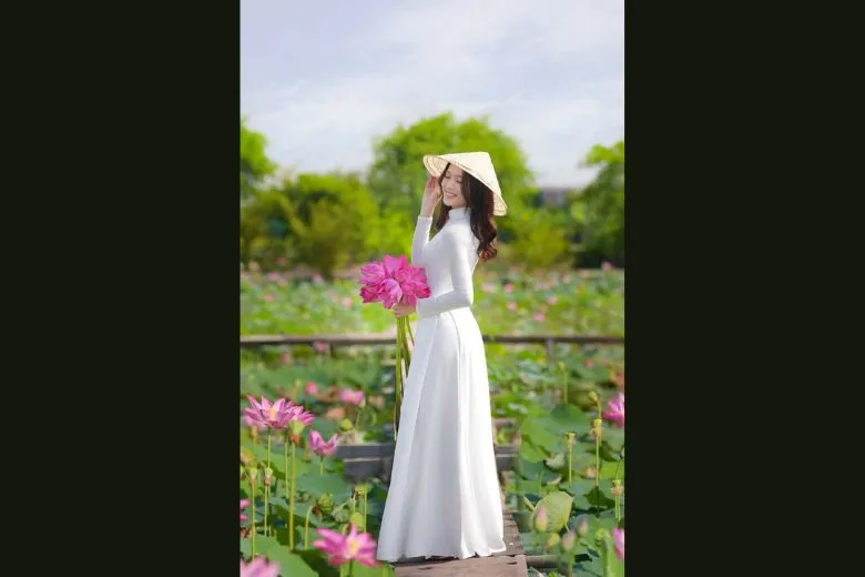 Nữ sinh áo dài trắng đội nón lá, mỉm cười khi bước đi