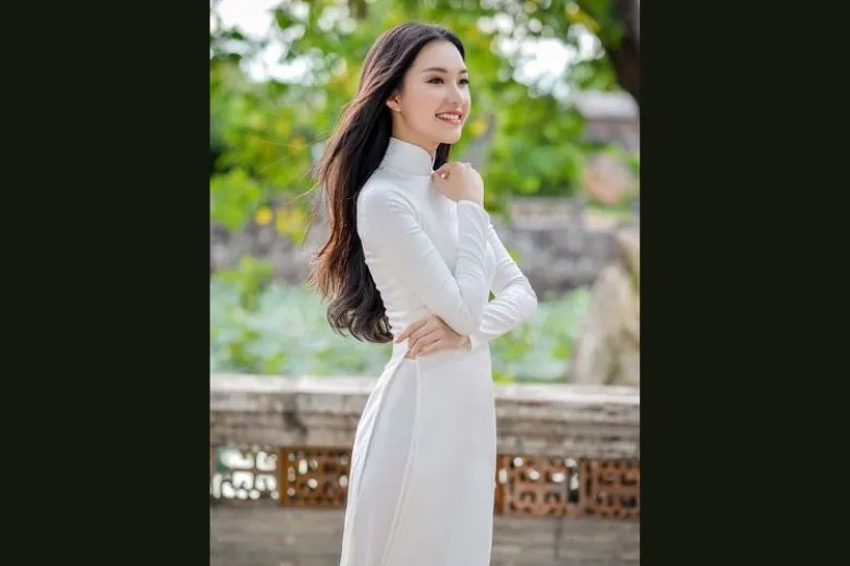 Nữ sinh áo dài trắng đội nón lá, tóc bay trong gió, tạo dáng chụp ảnh