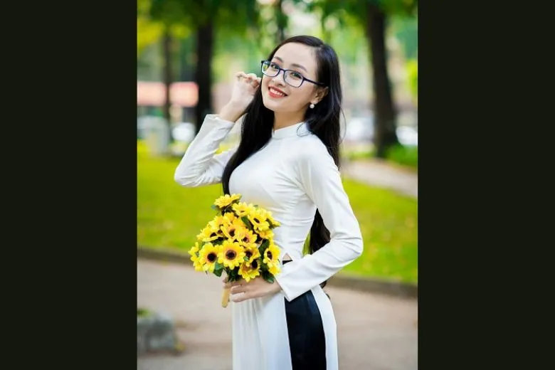 Nữ sinh áo dài trắng tạo dáng với bó hoa và cử chỉ tay