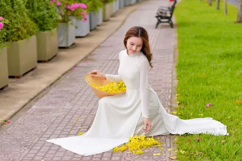 Nữ sinh áo dài trắng cúi đầu, tay vuốt tóc