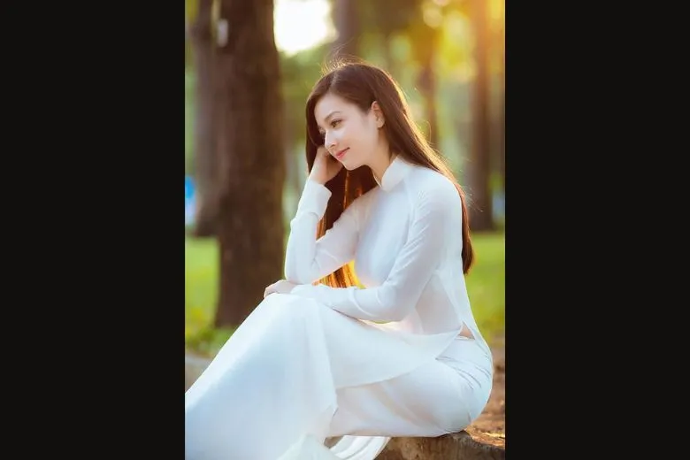 Nữ sinh áo dài trắng cúi đầu, tay nhẹ nhàng giữ tà áo