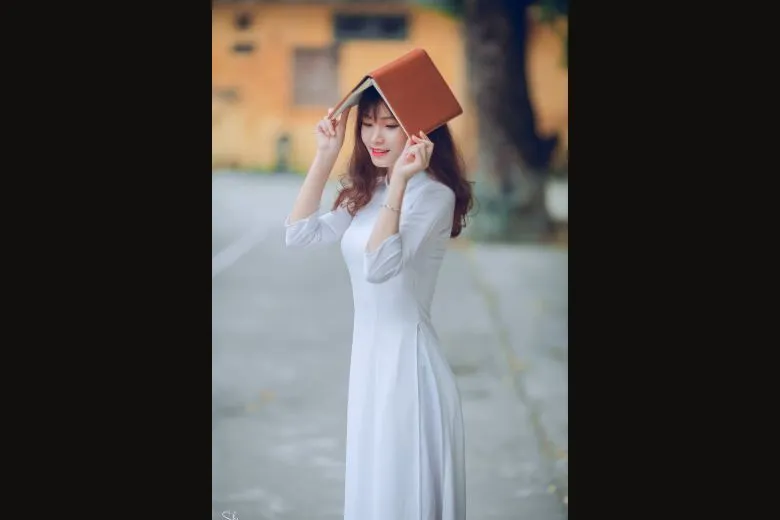Nữ sinh áo dài trắng ngồi ghế đá đọc sách/nhật ký