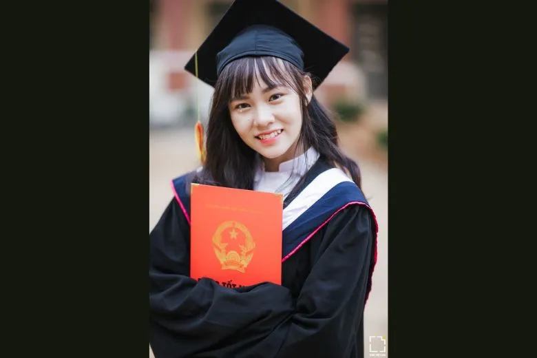 Nữ sinh áo dài trắng đứng thẳng, cầm bằng tốt nghiệp, mỉm cười
