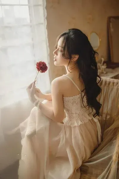 Nàng thơ nằm trên giường với chăn ga trắng, bối cảnh phòng ngủ lãng mạn.