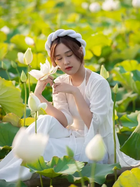 Nàng thơ ngồi bên hồ sen nở rộ, thể hiện vẻ đẹp thanh thoát.