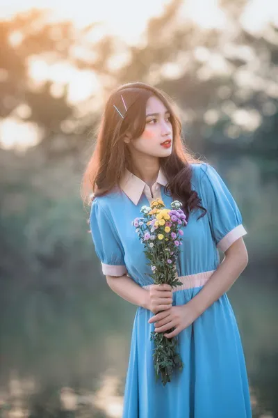 Cô gái trong bộ váy dài đi dạo dưới ánh nắng chiều vàng, tạo không khí mơ màng.