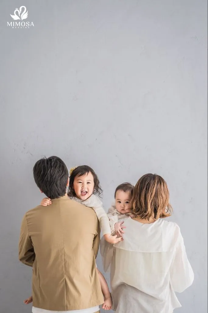 Bố mẹ đứng và hai con đứng hai bên trong studio