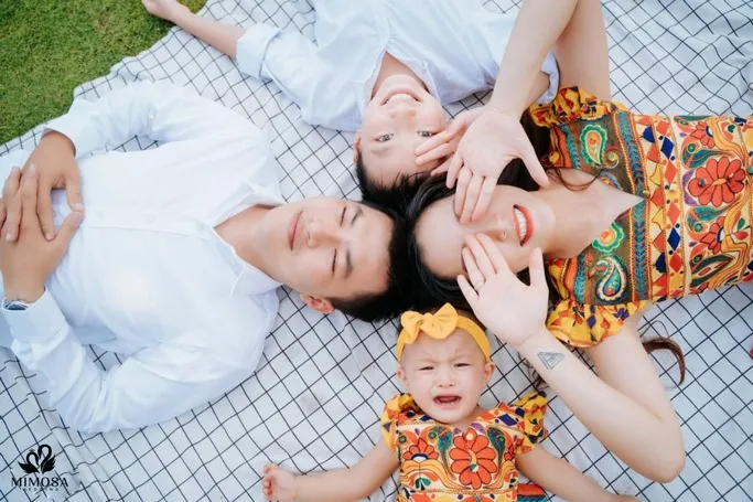 Gia đình 4 người nằm trên cỏ chụp ảnh