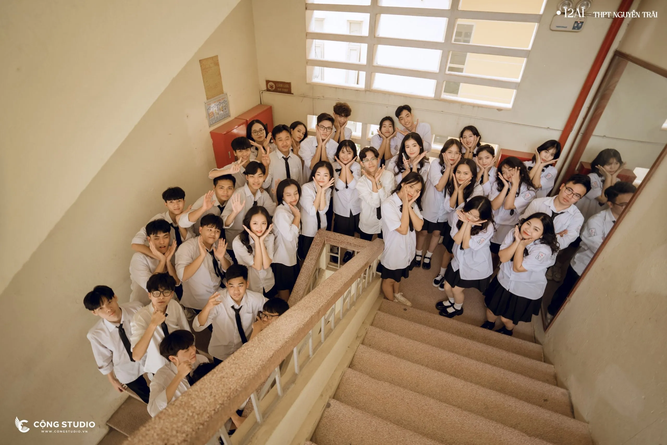Nhóm học sinh tươi cười nhìn lên camera chụp ảnh tập thể