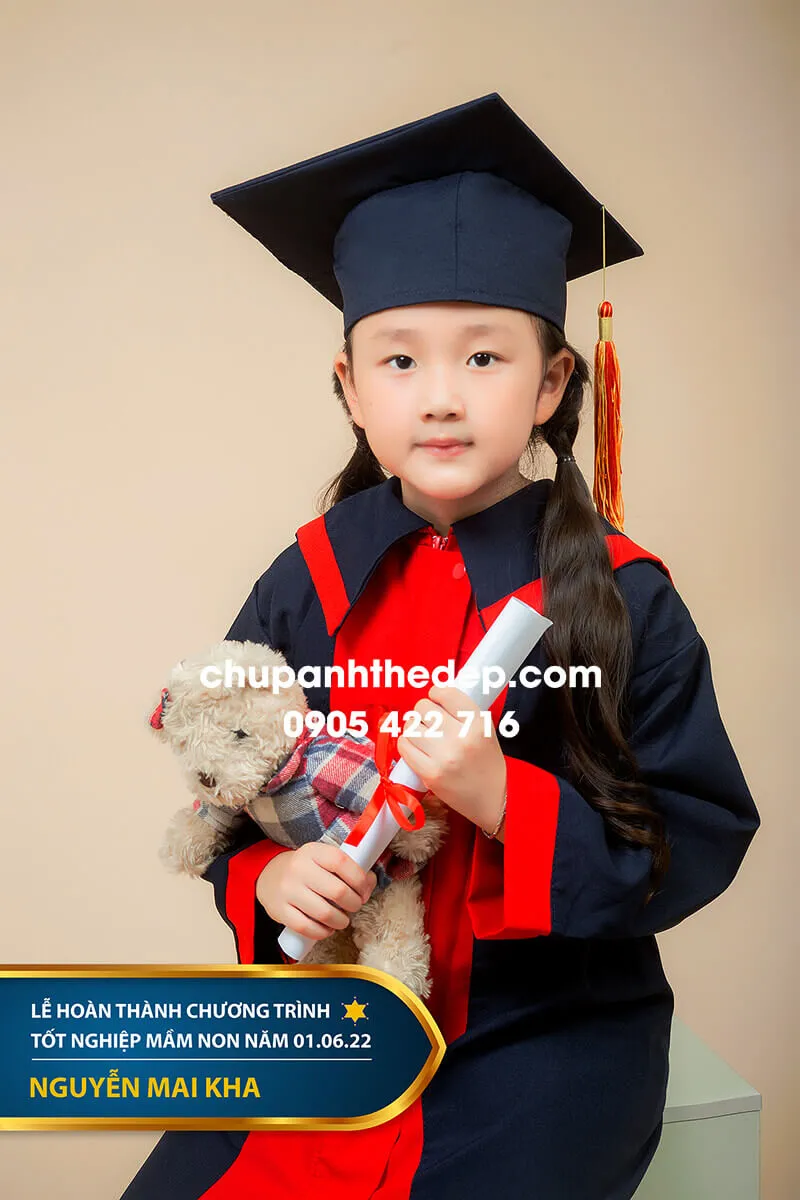 Bé gái mặc áo cử nhân mầm non cầm bằng tốt nghiệp giả