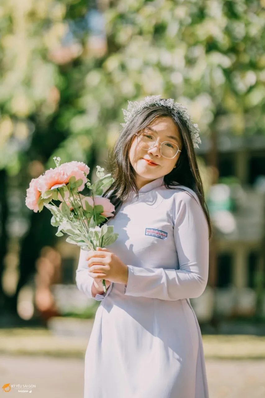 Cô gái với bó hoa lớn, tạo dáng chụp ảnh kỷ yếu cùng áo dài