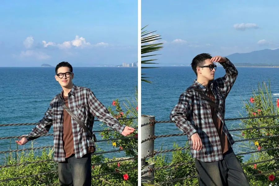 Chàng trai đứng cạnh lan can biển, một tay dang nhẹ