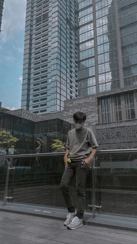 Chàng trai đứng nghiêng người dựa vào lan can sân thượng