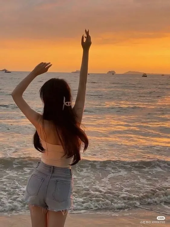 Cô gái quay lưng ngắm hoàng hôn trên biển