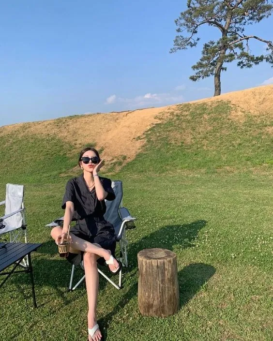 Cô gái ngồi trên ghế camping ngửa mặt lên trời