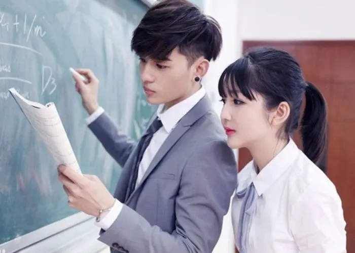 Cặp đôi bạn thân nam nữ tạo dáng chụp ảnh kỷ yếu trên bục giảng lớp học